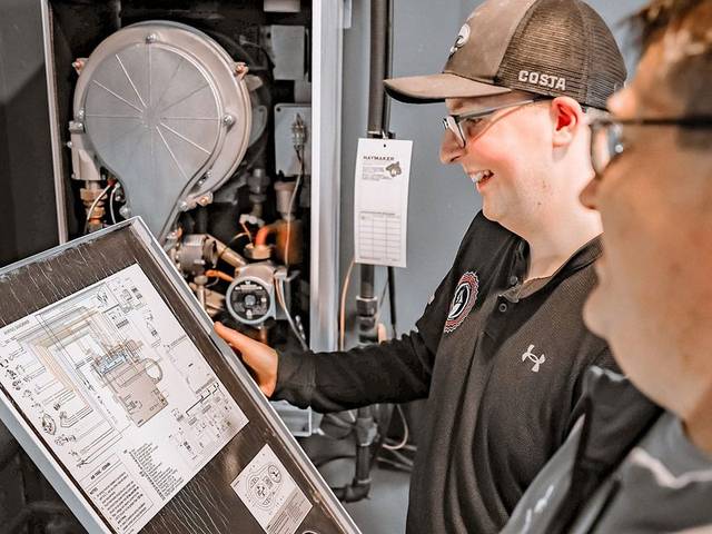 A Green Comfort Systems technician fitting a fresh filter during a gas furnace service call
